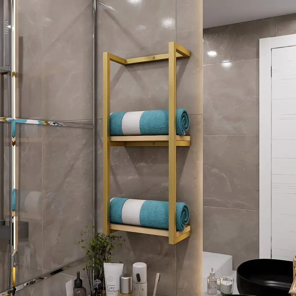 White metal bathroom shelf with a light wood base, holding neatly folded blue towels, installed on a beige tiled wall with bathroom accessories below