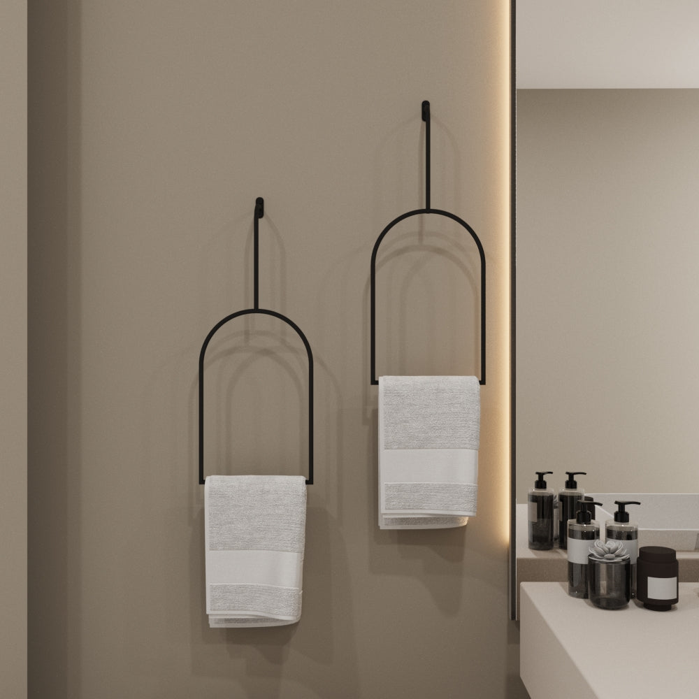 Minimalist black arched towel rings mounted on a neutral beige bathroom wall, holding white towels, adding an elegant and modern touch to the bathroom decor.