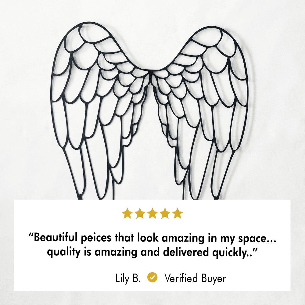 A close-up of metal angel wings wall art displayed on a white wall. Below the wall art is a 5-star customer review from a verified buyer, Lily B., stating: "Beautiful pieces that look amazing in my space... quality is amazing and delivered quickly."