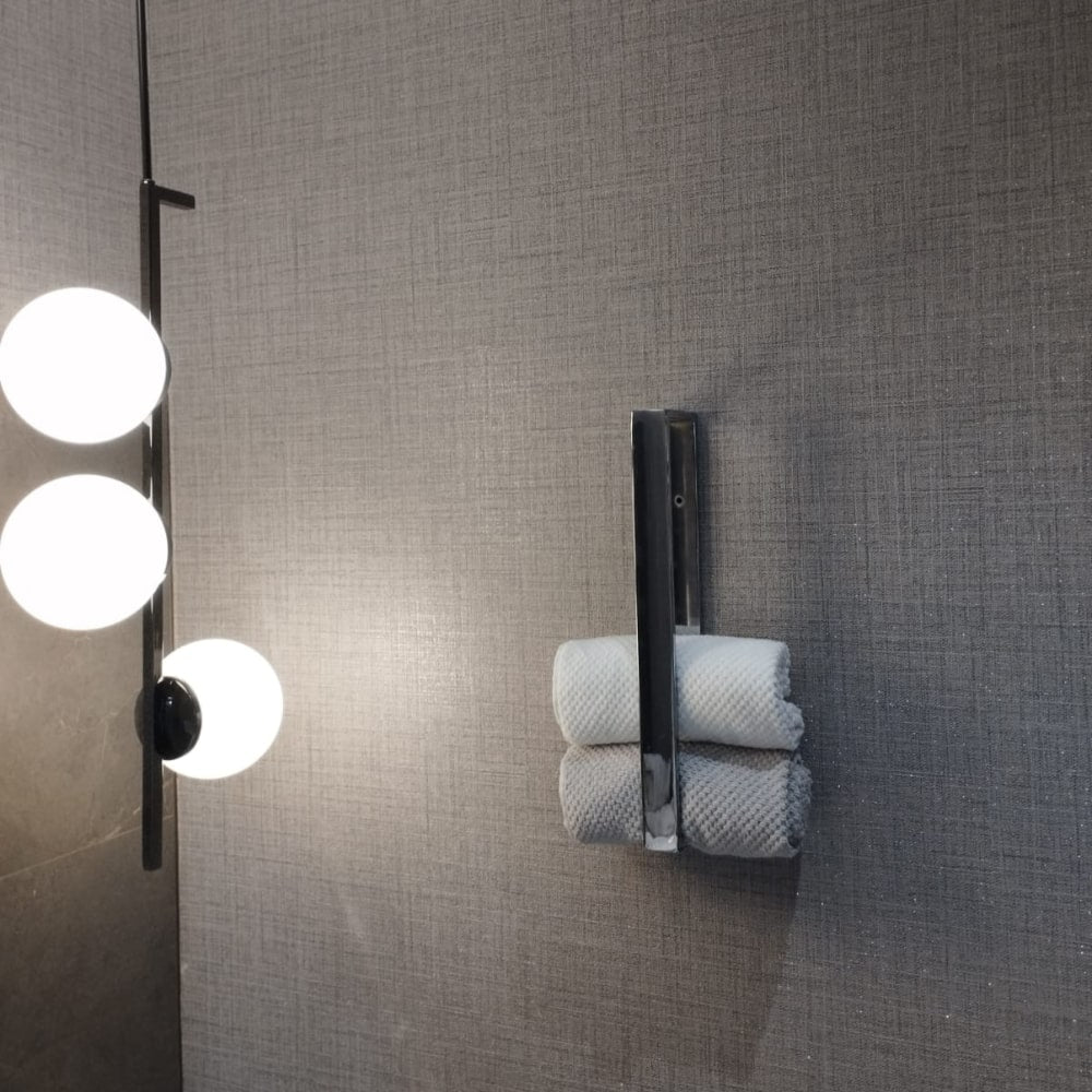 A bathroom scene showing a chrome towel holder with towels and a modern light fixture featuring round white bulbs