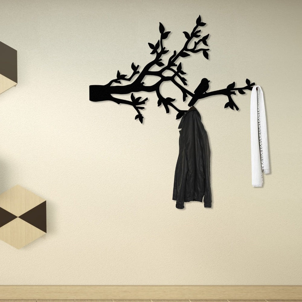 A black metal wall-mounted coat rack featuring a bird perched on branches. The rack holds a black coat and a white scarf, offering a stylish and functional solution for entryway or hallway decor.