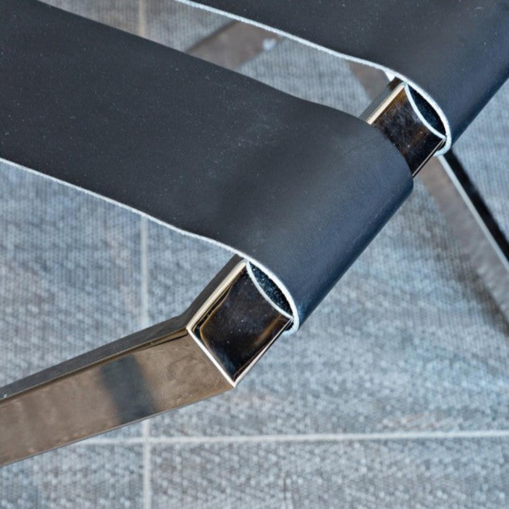 A close-up view of a black strap on a shiny metal luggage rack, highlighting its sturdy and elegant construction