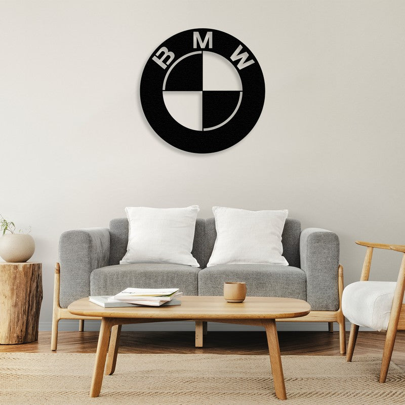 Black BMW-inspired metal wall art mounted on a neutral wall above a stylish gray sofa with white cushions, complemented by a wooden coffee table and rustic side decor.