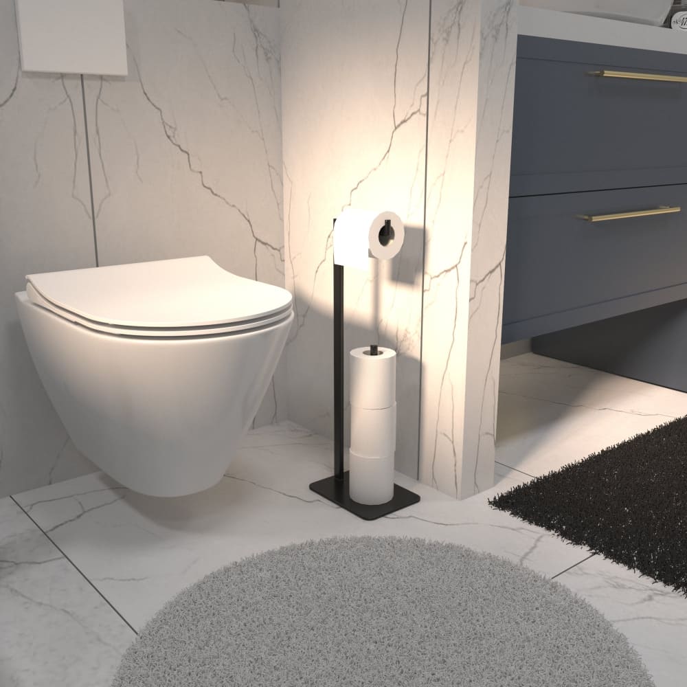  sleek black freestanding toilet paper holder with a modern design, holding one roll on top and three spare rolls stacked below. The bathroom features marble walls and flooring, a wall-mounted toilet, a blue vanity with gold handles, and soft gray and black rugs for added comfort.