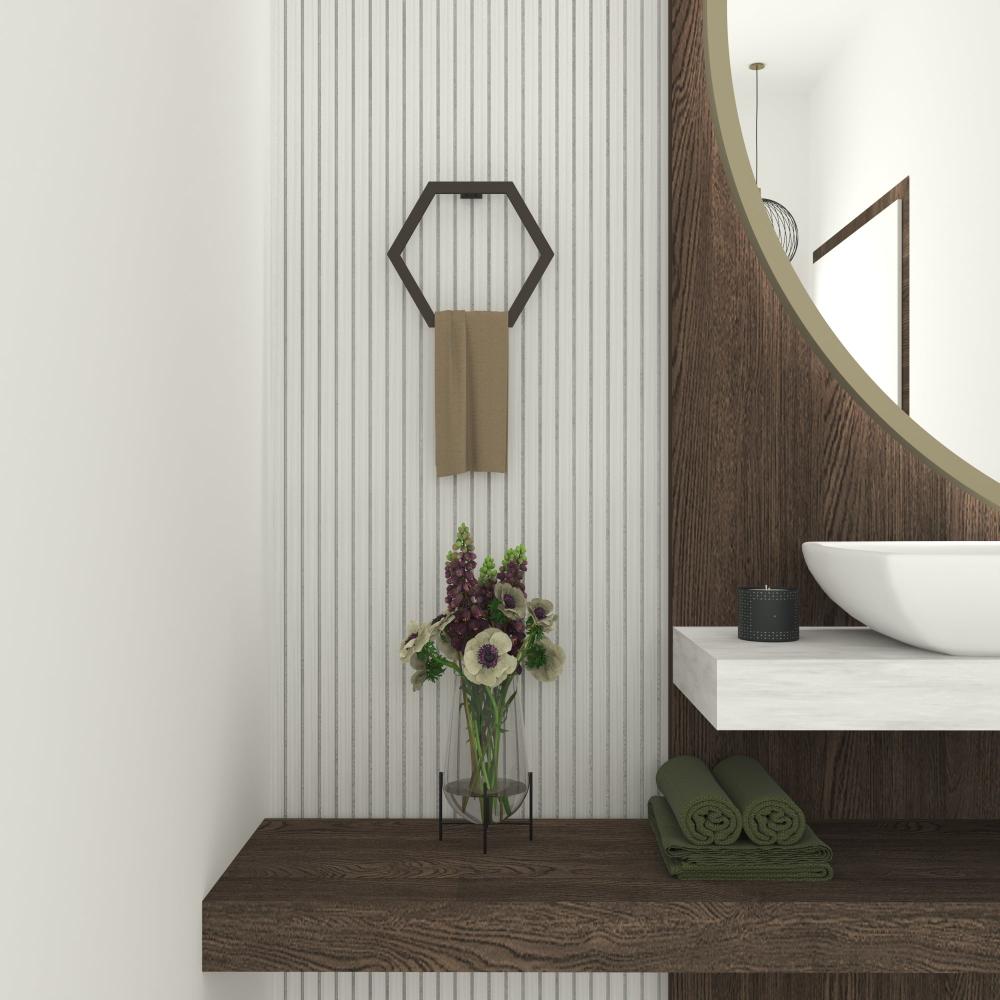 Black hexagon towel holder mounted on a bathroom wall with a beige towel, alongside a vase of flowers and a round mirror over a wooden shelf.