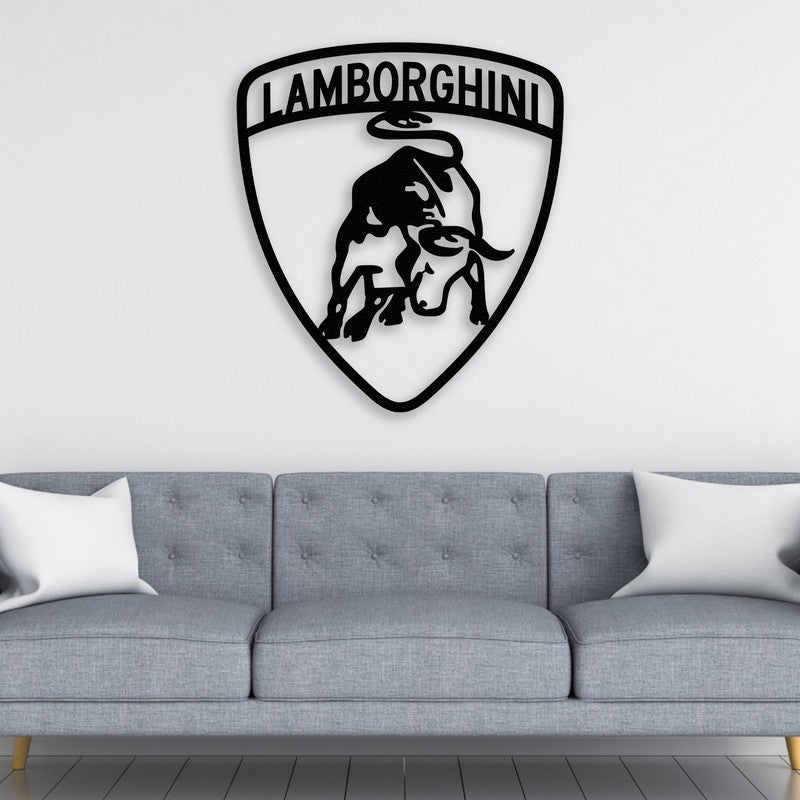 A bold black Lamborghini-inspired metal wall art featuring a charging bull, mounted above a modern gray tufted sofa with white accent pillows. The setting reflects a sleek and contemporary automotive-themed decor.