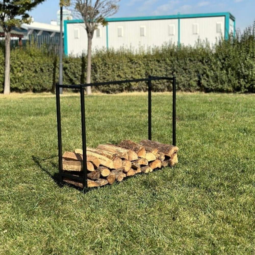 A black metal log holder filled with firewood, placed outdoors on a grassy lawn under a sunny sky.