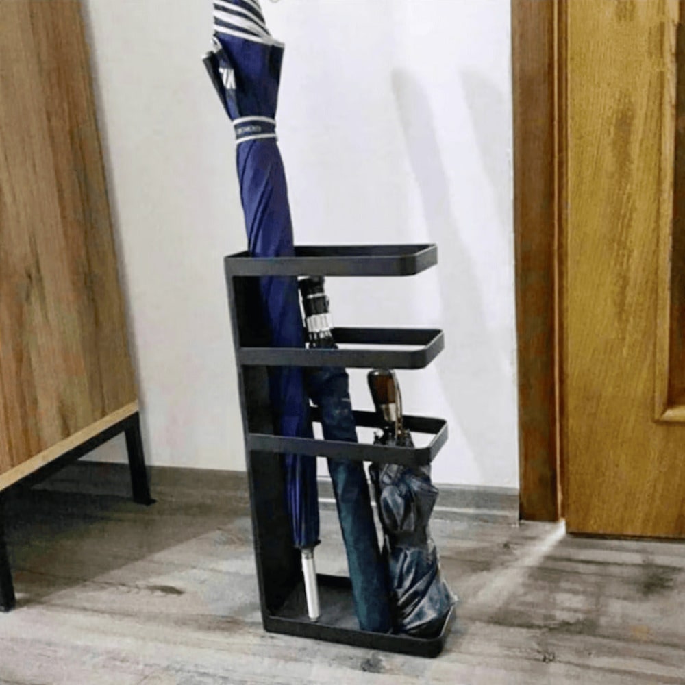 A black umbrella stand holding multiple umbrellas, placed in a contemporary interior with wood and neutral accents