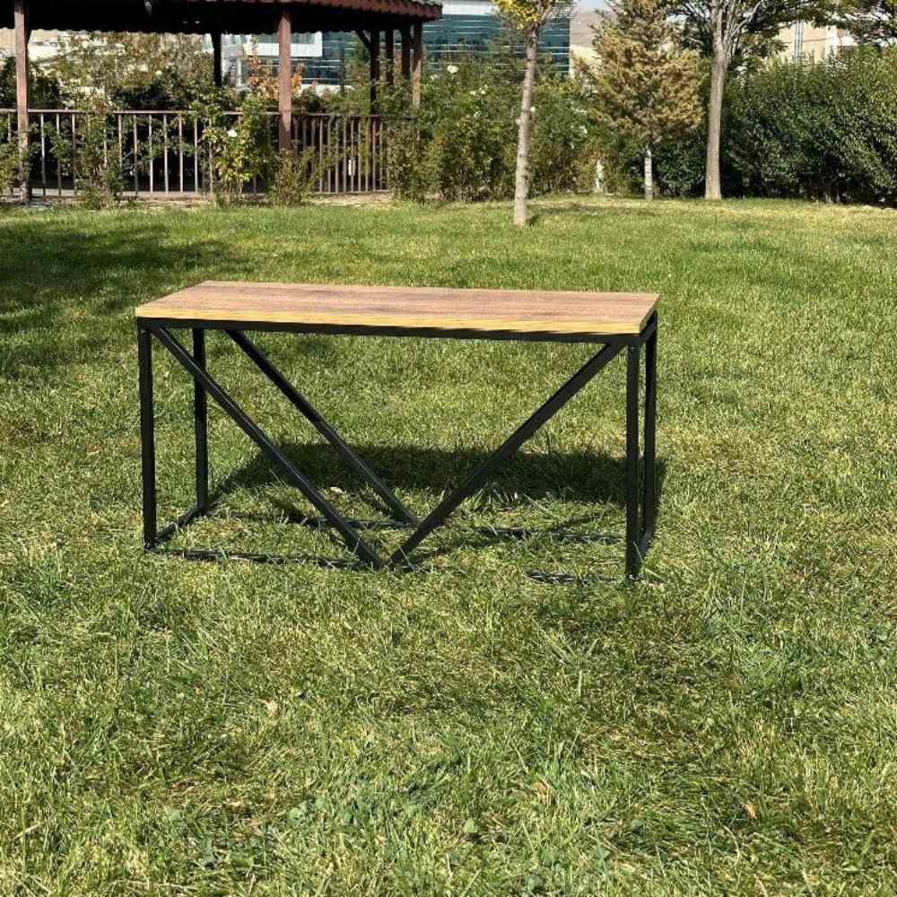 An empty black metal wood rack with a wooden top and V-shaped design, standing on a green lawn in an outdoor environment.