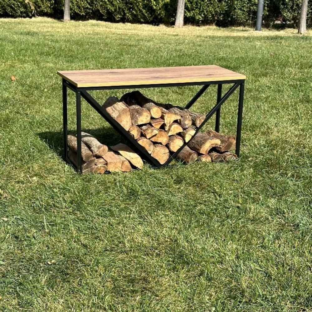 A black metal wood rack with a wooden top, showcasing stacked firewood underneath, placed on a grassy outdoor area