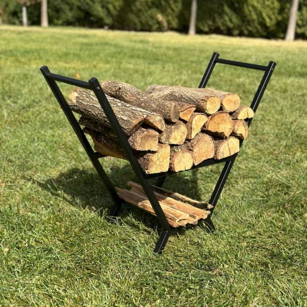 A black portable V-shaped wood rack outdoors on green grass, holding a large amount of firewood, showcasing its sturdy and compact design.
