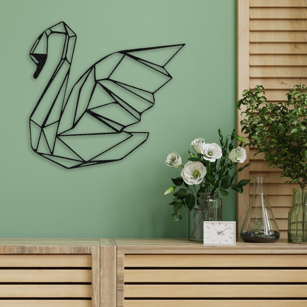 Black swan metal wall art on a mint green wall above a wooden cabinet adorned with white flowers and a small clock.