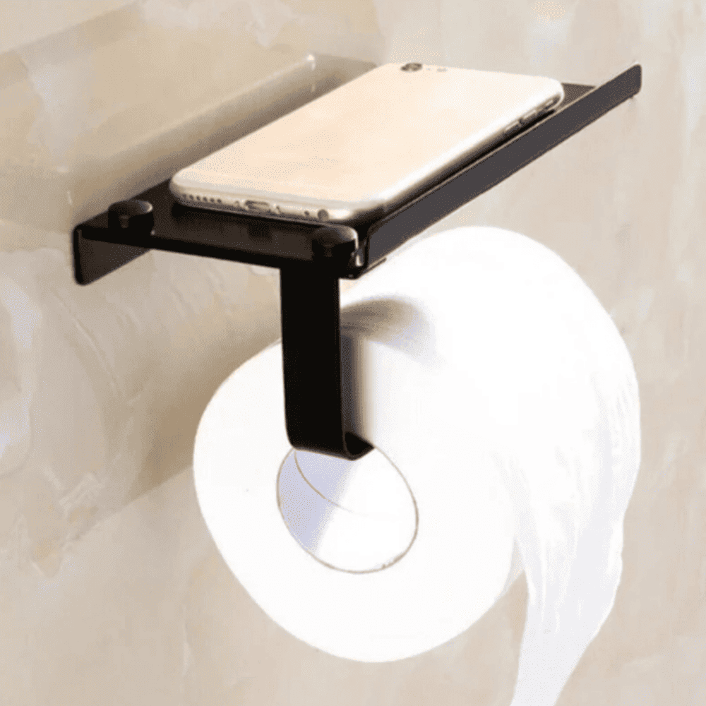 Close-up of a black wall-mounted toilet paper holder with a shelf holding a smartphone, displayed in a modern bathroom