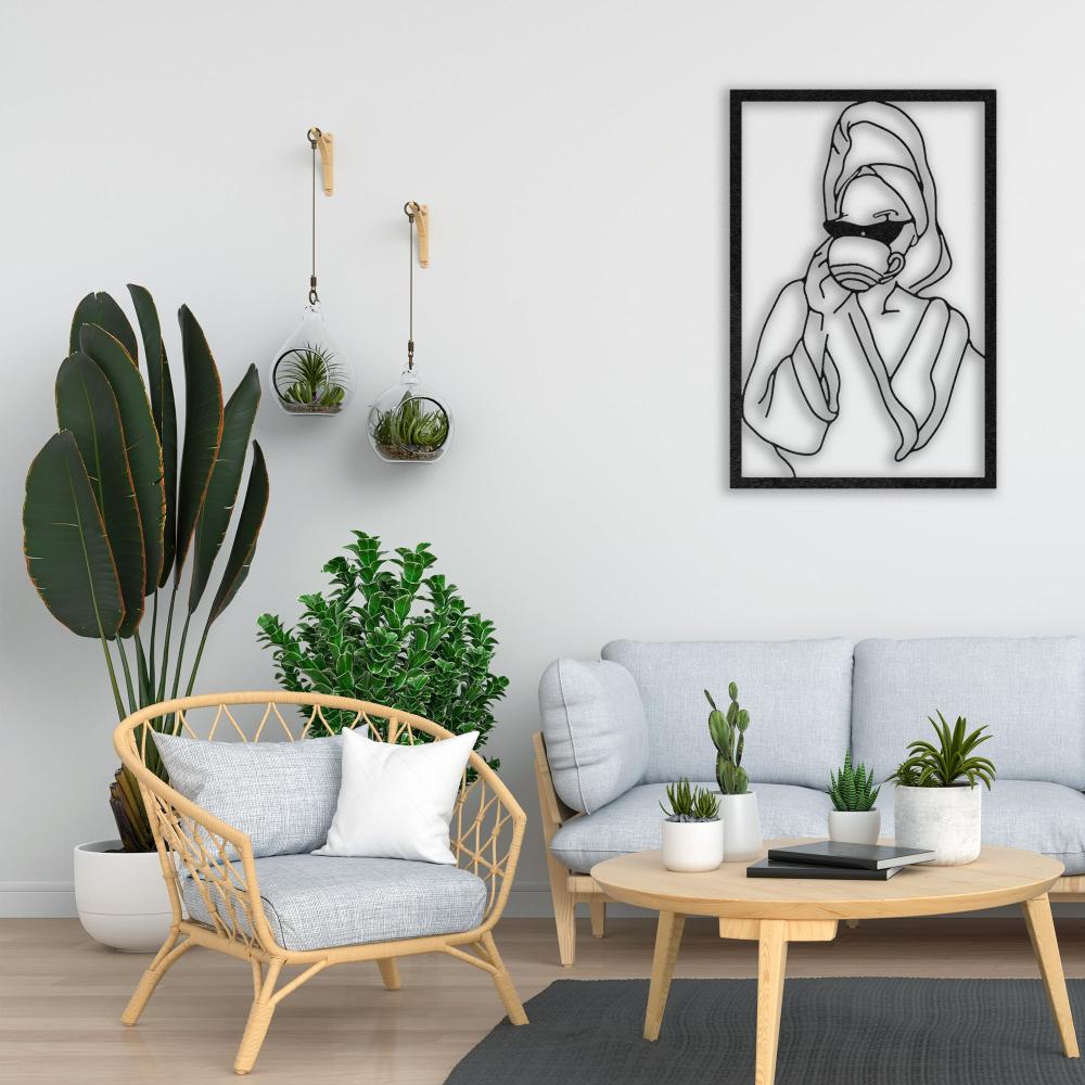 Modern living room featuring a framed metal wall art of a woman drinking coffee, complemented by a light gray sofa, a wicker armchair with a white pillow, and a wooden coffee table surrounded by vibrant green plants and hanging glass terrariums.