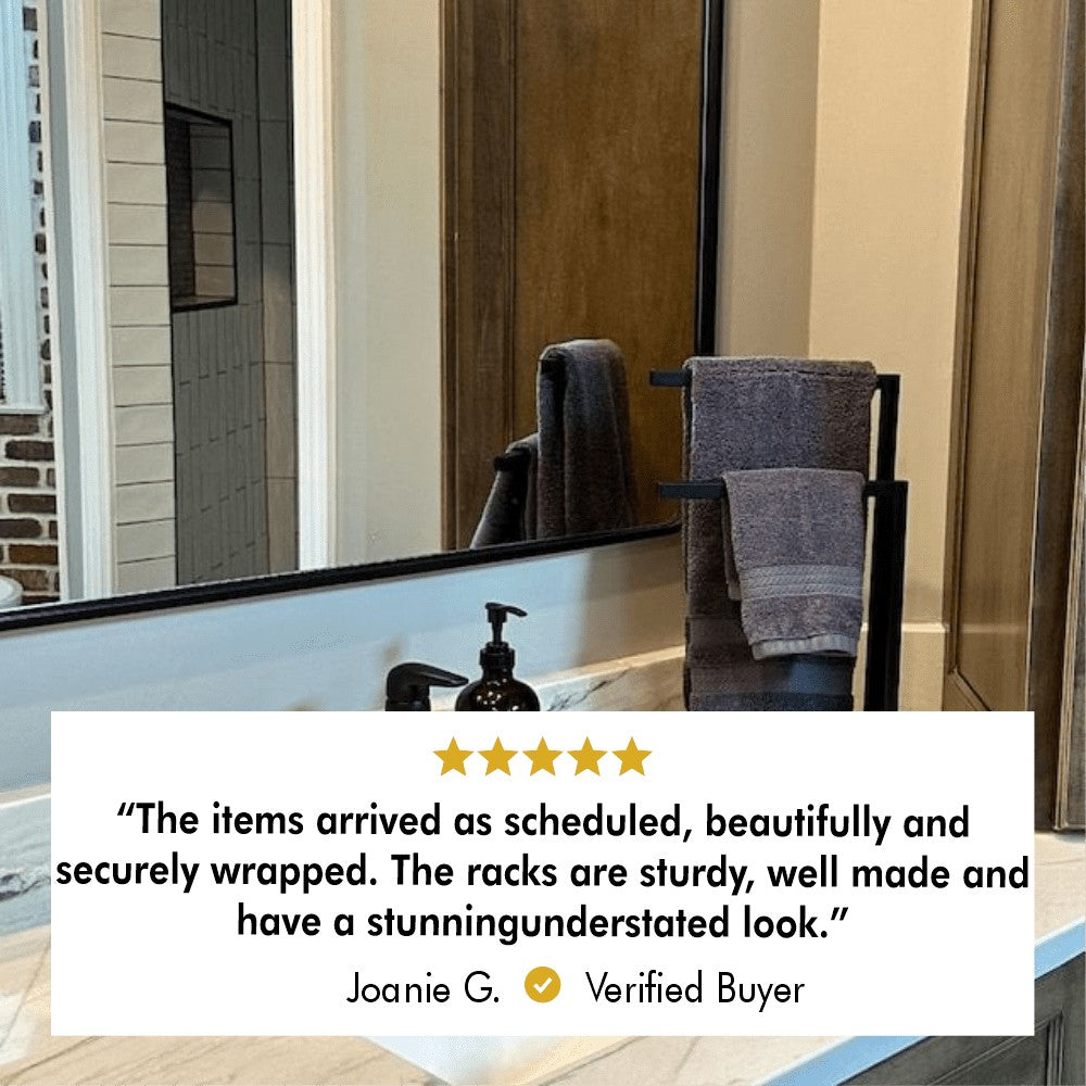 A black countertop towel holder shown next to a sink, with user review text below, highlighting its durable construction and stunning look as appreciated by a satisfied buyer.