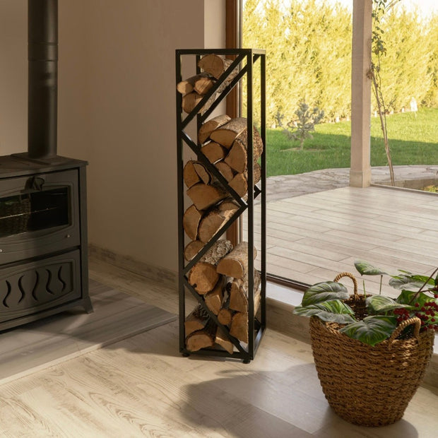 A modern and elegant metal log rack filled with firewood, placed next to a black stove in a cozy living room with a natural wood floor and large windows.