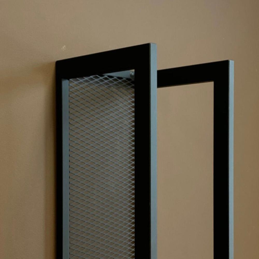 Close-up view of the edge of a wall-mounted firewood holder showcasing its high-quality black metal finish and mesh design.