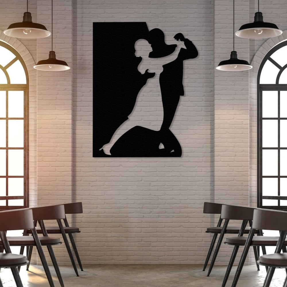 Black silhouette metal wall art of a dancing couple mounted on a brick wall in a well-lit cafe or restaurant with arched windows and modern decor. 