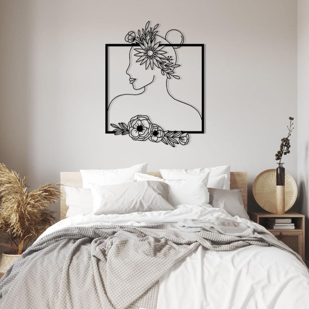 Black floral silhouette wall art of a woman with a flower crown, mounted above a wooden bed with white bedding, neutral tones, and dried pampas grass as decor.