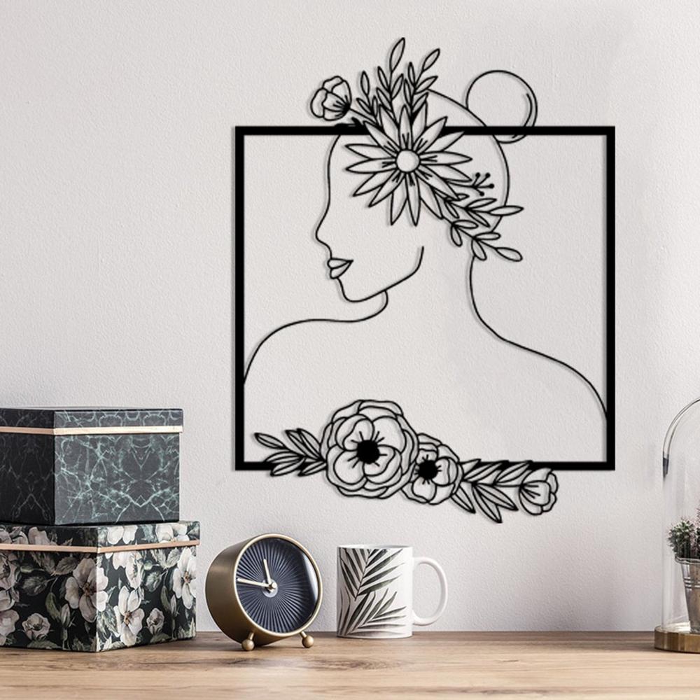 Detailed view of floral-themed metal wall art featuring a woman's silhouette with floral patterns, displayed on a wall with modern decor, including a clock and decorative items.