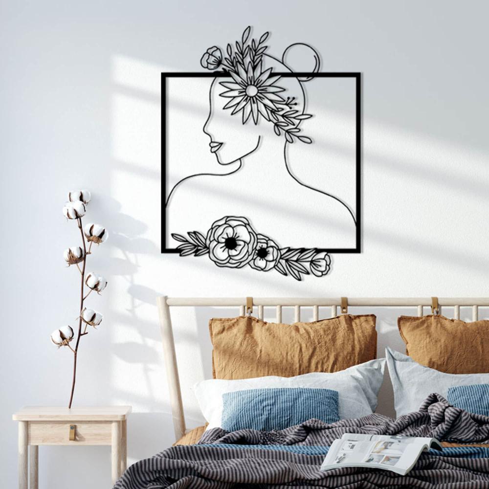  Detailed view of floral-themed metal wall art featuring a woman's silhouette with floral patterns, displayed on a wall with modern decor, including a clock and decorative items.