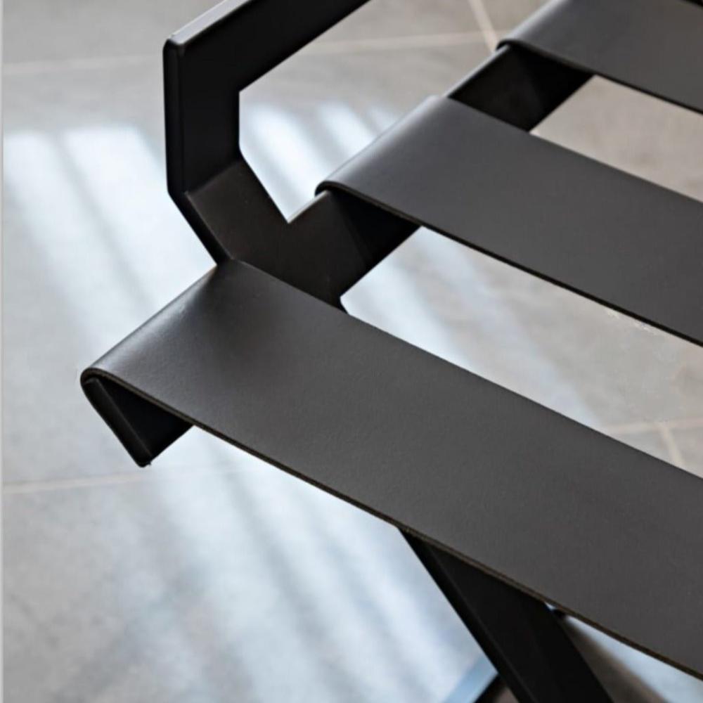 Close up view of a foldable luxury luggage rack with genunie leather straps for guest room minimalist luxury design