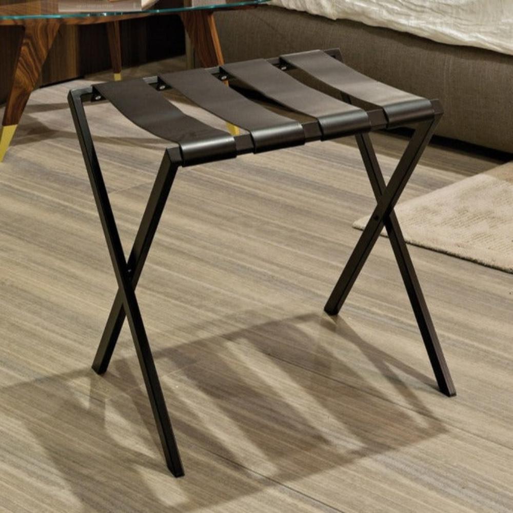 A foldable black metal luggage rack with four sturdy leather straps, designed for bedroom or hotel use, placed on a wooden floor.