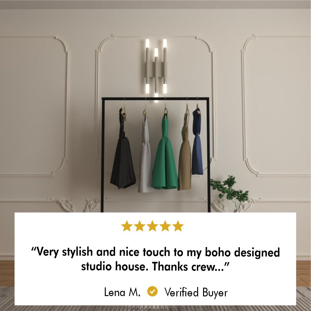 Free-standing clothes rail showcasing dresses in a stylish room setting with elegant wall moldings, featuring a minimalist black metal design. The product is highlighted by a 5-star review: "Very stylish and nice touch to my boho designed studio house. Thanks crew..." – Lena M., Verified Buyer.