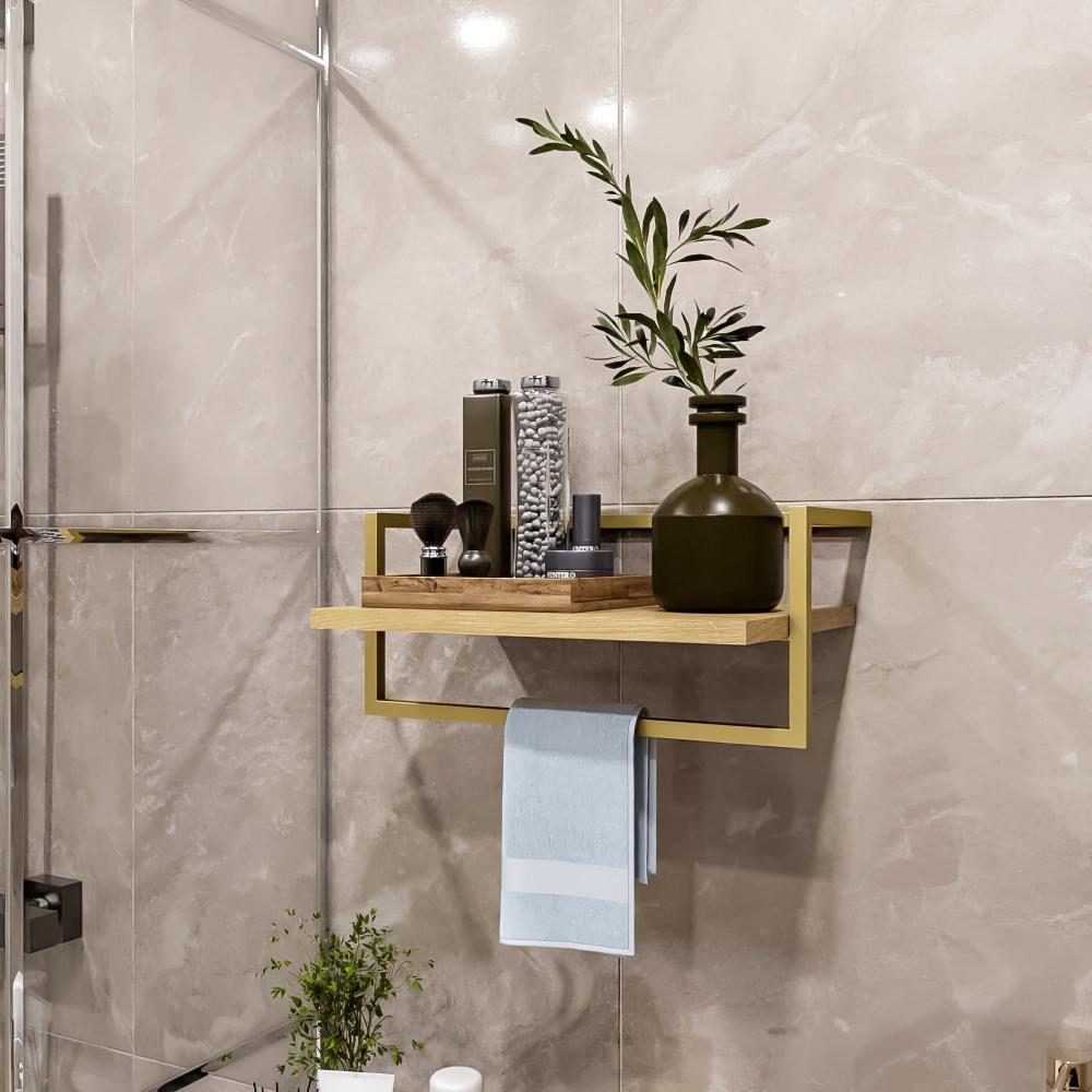 A modern bathroom shelf with a gold metal frame and wooden plank, styled with green and neutral decor, and a towel hanging below.