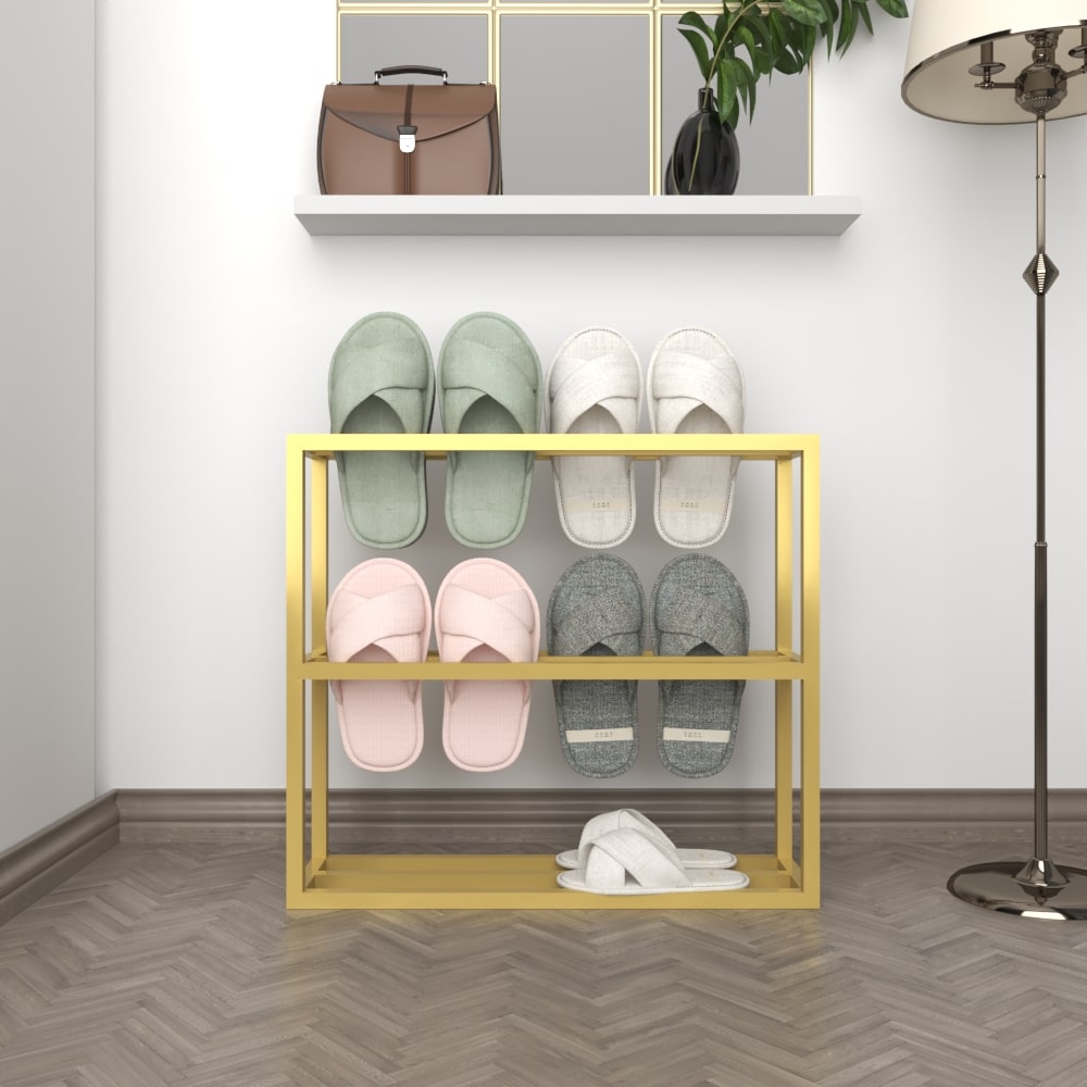 A gold-colored metal slipper rack holding two pairs of white and green slippers, blending functionality with a stylish finish against a textured wall