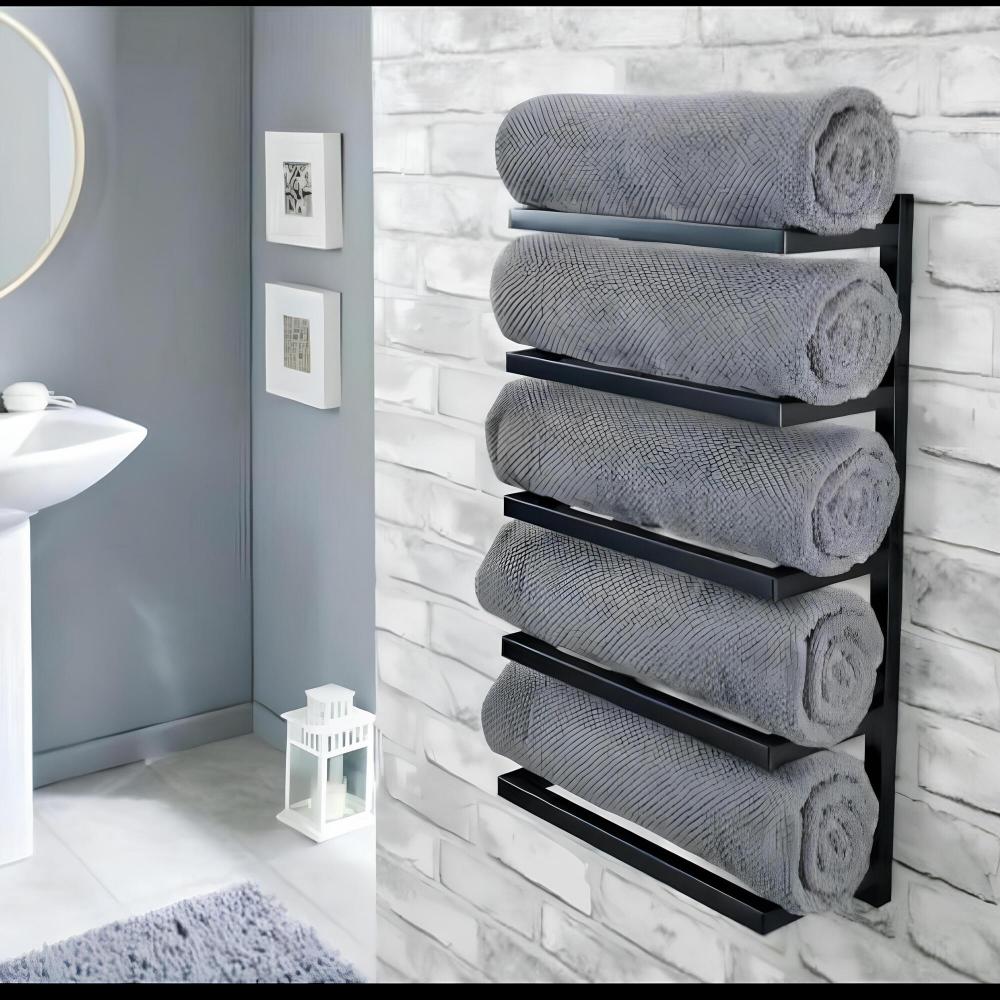 Wall-mounted black towel rack with five tiers, holding rolled gray towels against a white brick wall in a modern bathroom with a round mirror and minimalist decor