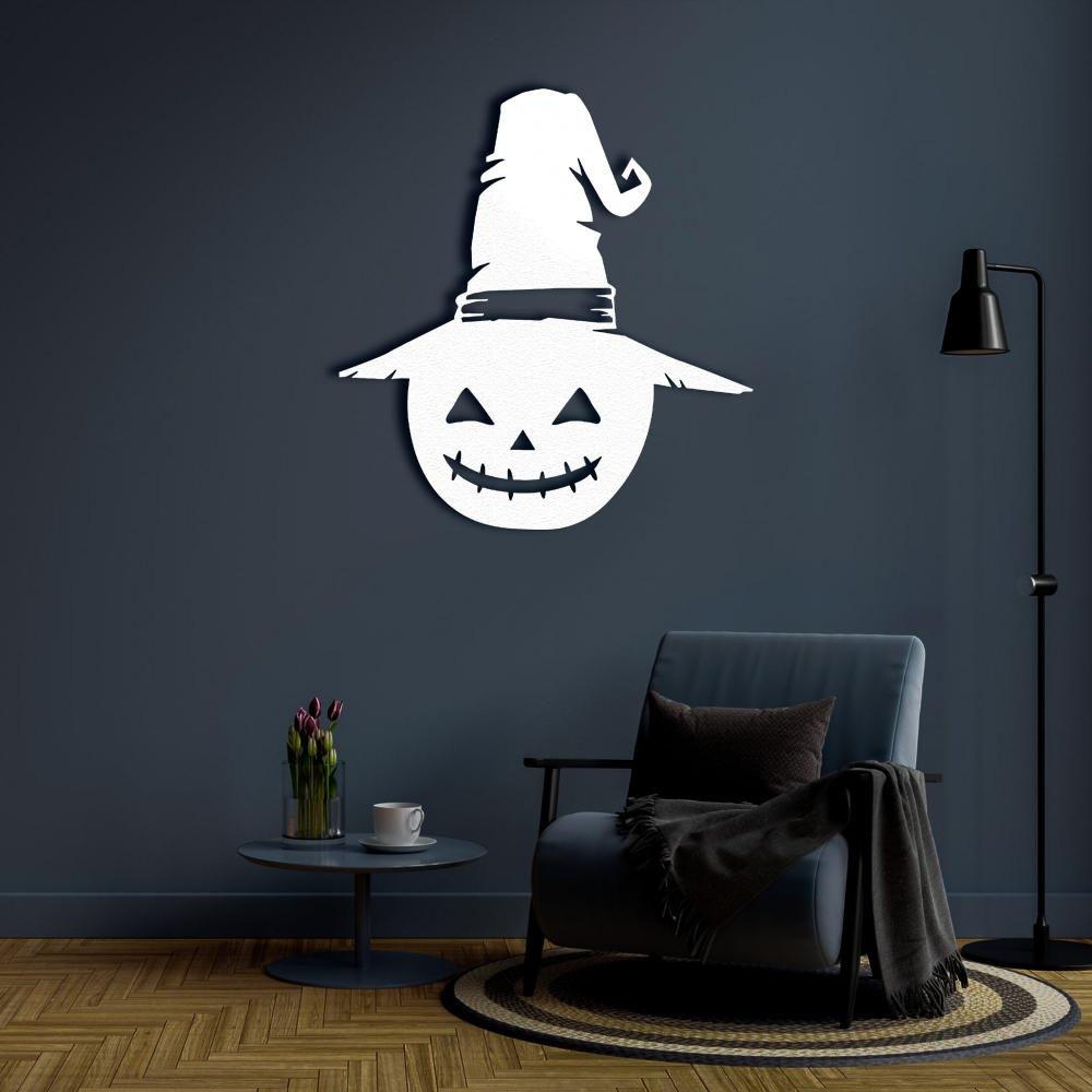 White metal Halloween wall art of a jack-o'-lantern with a witch's hat, mounted on a dark navy wall above a stylish armchair and coffee table.