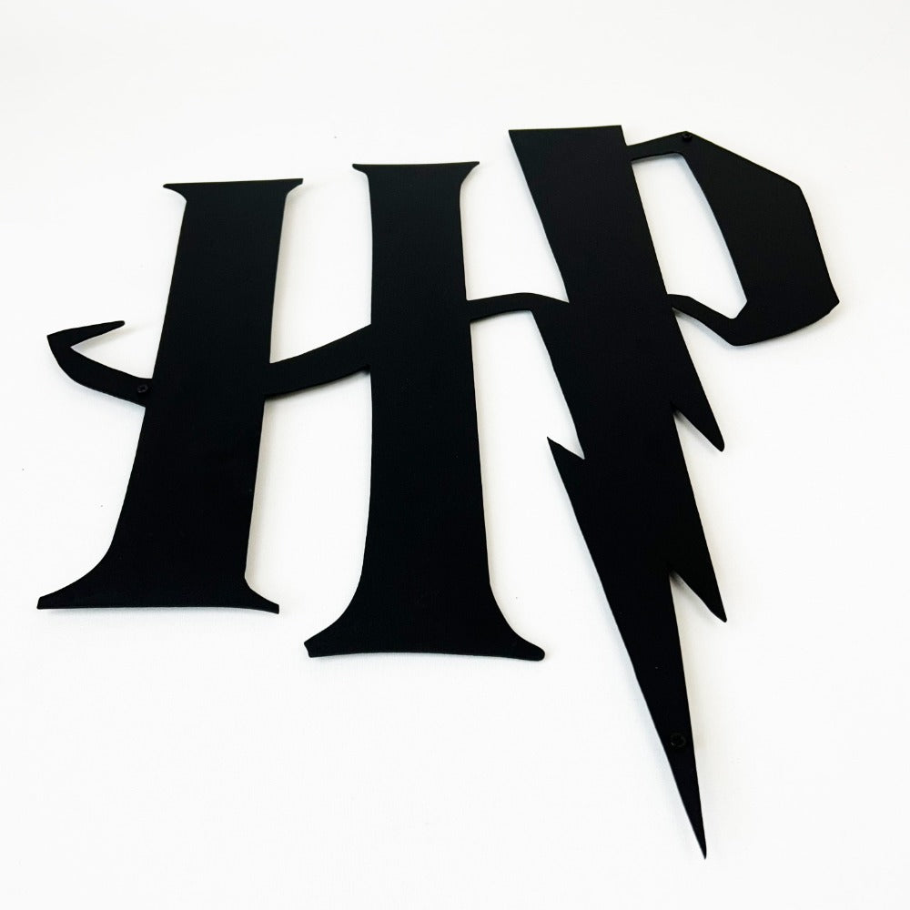 Close-up view of a black Harry Potter "HP" metal logo with a lightning bolt design, displayed on a white background.