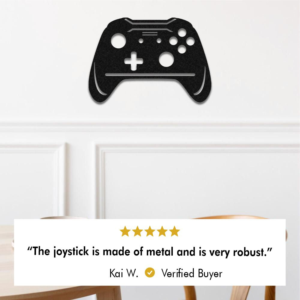 Video game controller-shaped metal wall art on a white brick wall above a vintage floral sofa, labels featuring a five star review: 'The joystick is made of metal and is very robust.' by Kai W. Verified Buyer