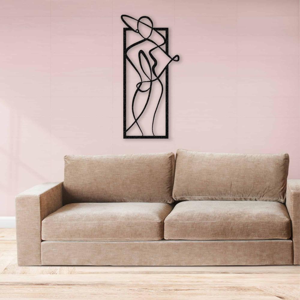 Modern metal wall art of a woman in a hat, centered on a pink wall above a beige sofa with a clean, minimalist aesthetic.