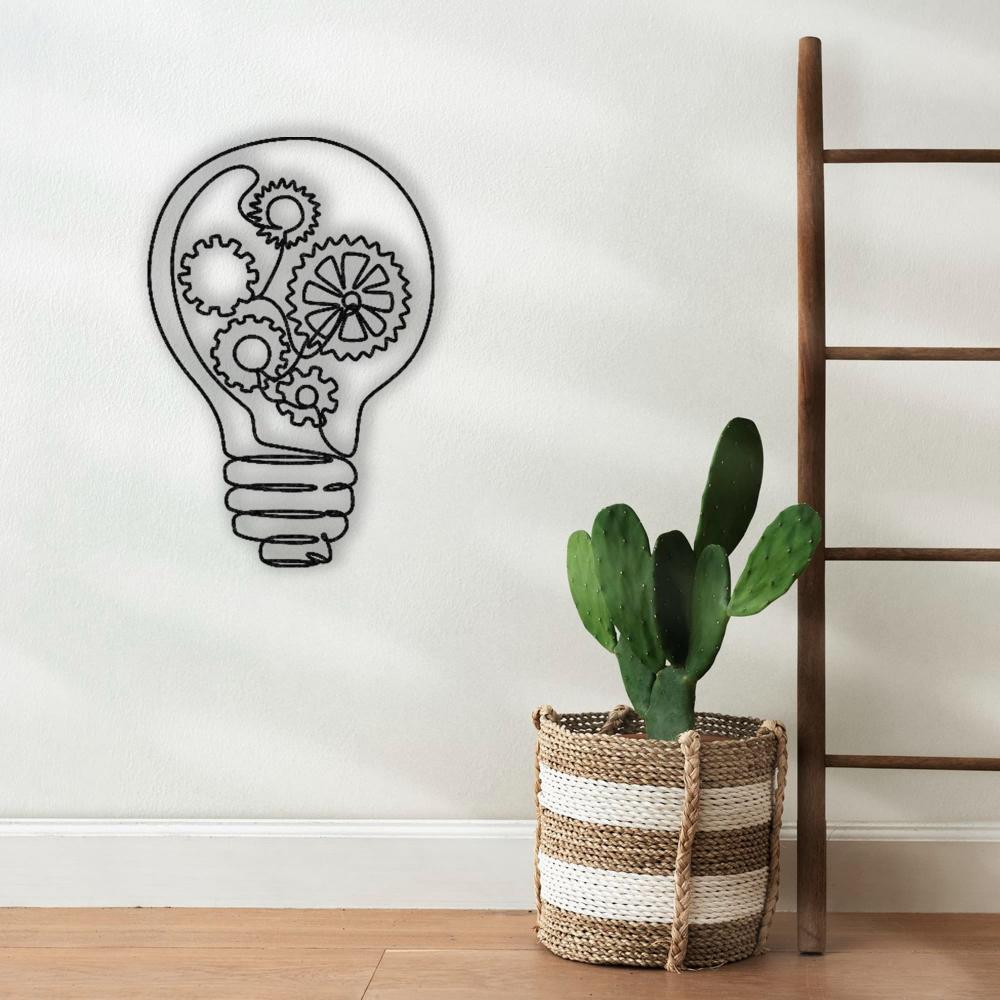  Light bulb-shaped metal wall art with intricate gear designs, displayed on a minimalist wall next to a woven basket containing a cactus and a wooden ladder.