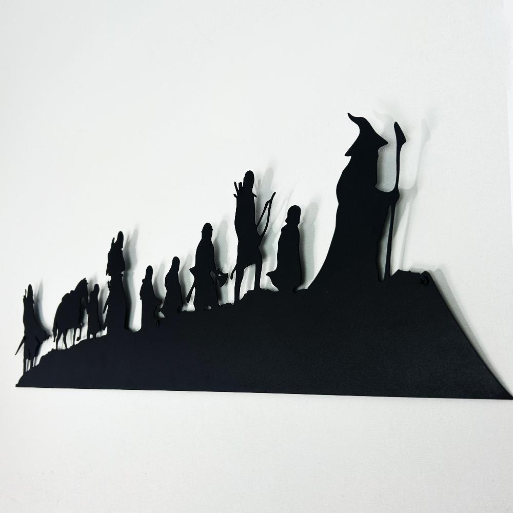 Angled view of black "Lord of the Rings" metal wall art featuring the silhouettes of the Fellowship of the Ring, emphasizing their distinct shapes and intricate details against a white background.