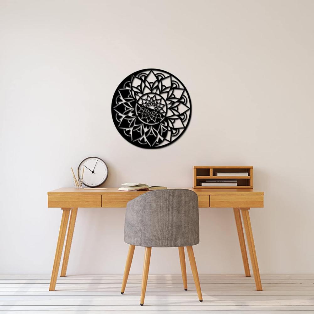 A detailed round floral mandala metal wall art mounted above a wooden office desk, styled with minimalistic accessories like books, a clock, and a chair.