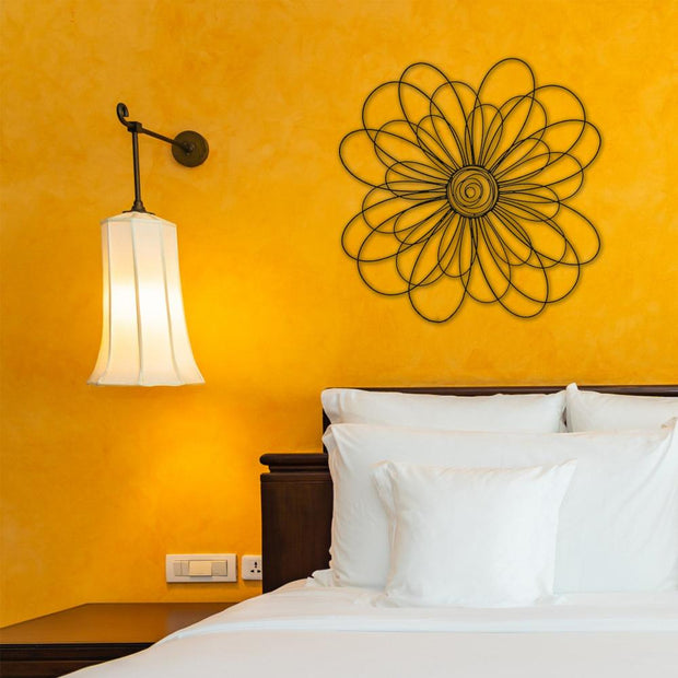 Stylish metal daisy wall art mounted above a bed with bright yellow walls, complementing the cozy and vibrant bedroom decor.