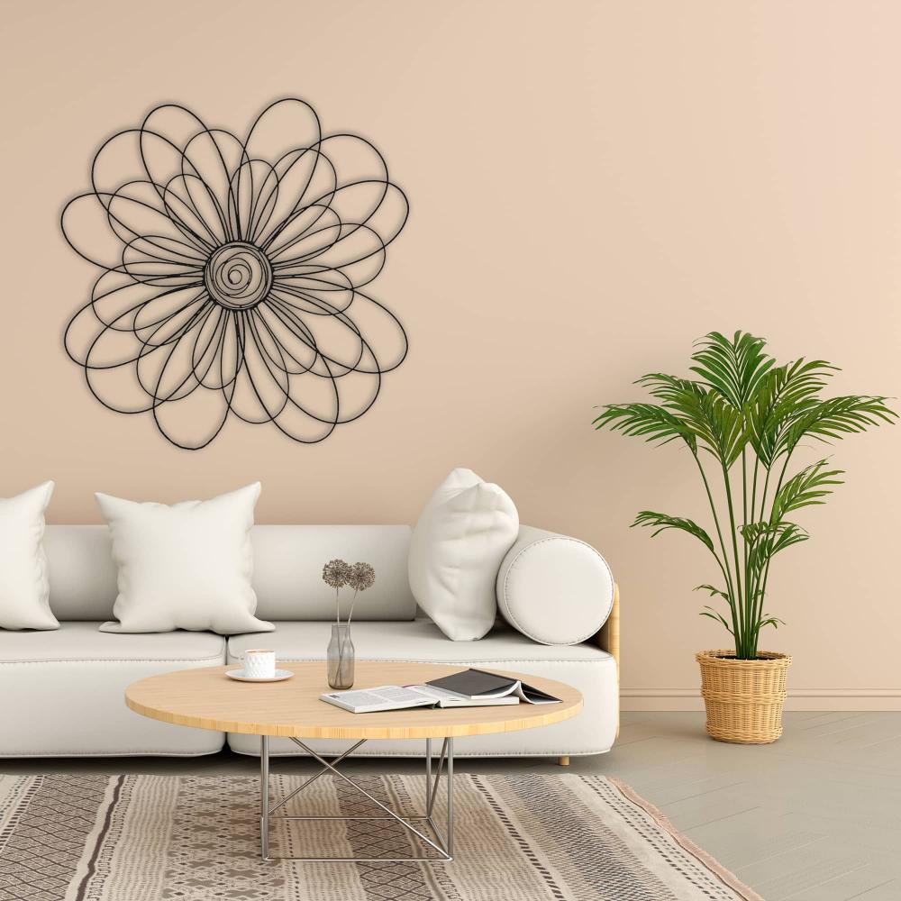 Modern metal daisy wall art displayed above a white sofa in a cozy living room with beige walls and a green potted plant.