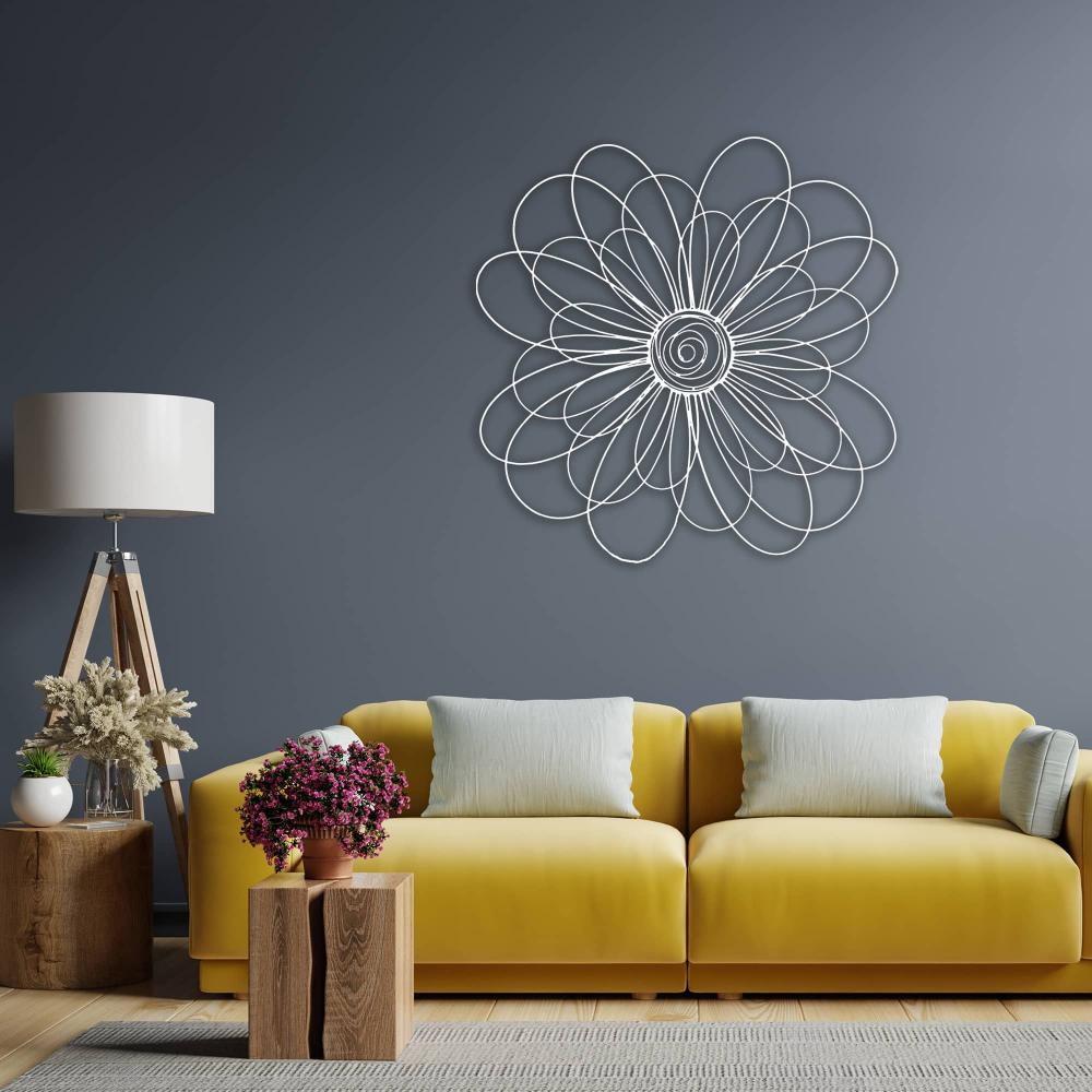 White metal daisy wall art with intricate loops displayed above a modern yellow sofa in a living room with a gray wall background.