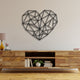 Black geometric heart-shaped wall art with intersecting lines, mounted above a rustic wooden console table decorated with books, a yellow lamp, and a small vase.