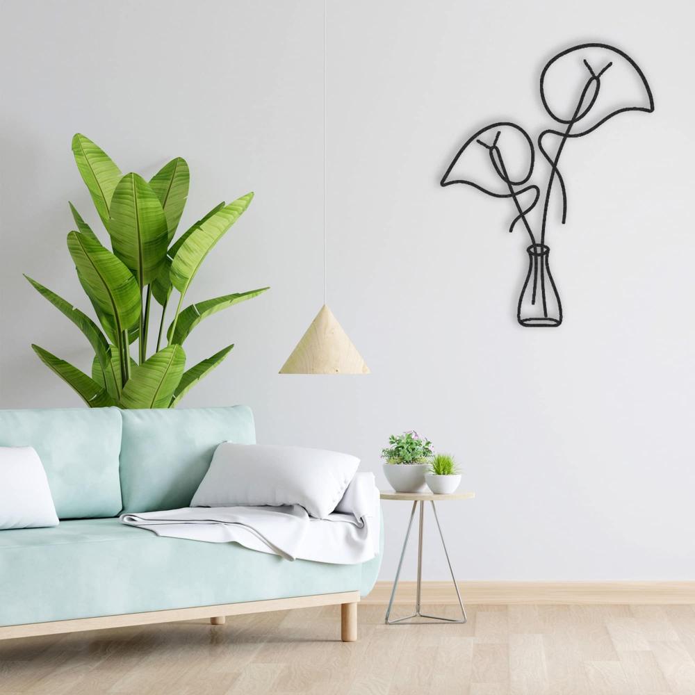 Black metal wall art featuring abstract leaves in a vase on a white wall, complemented by a light green sofa with white pillows. A modern triangular pendant light hangs above, and a side table with small potted plants adds a touch of greenery alongside a tall banana plant for a fresh, serene living room ambiance.