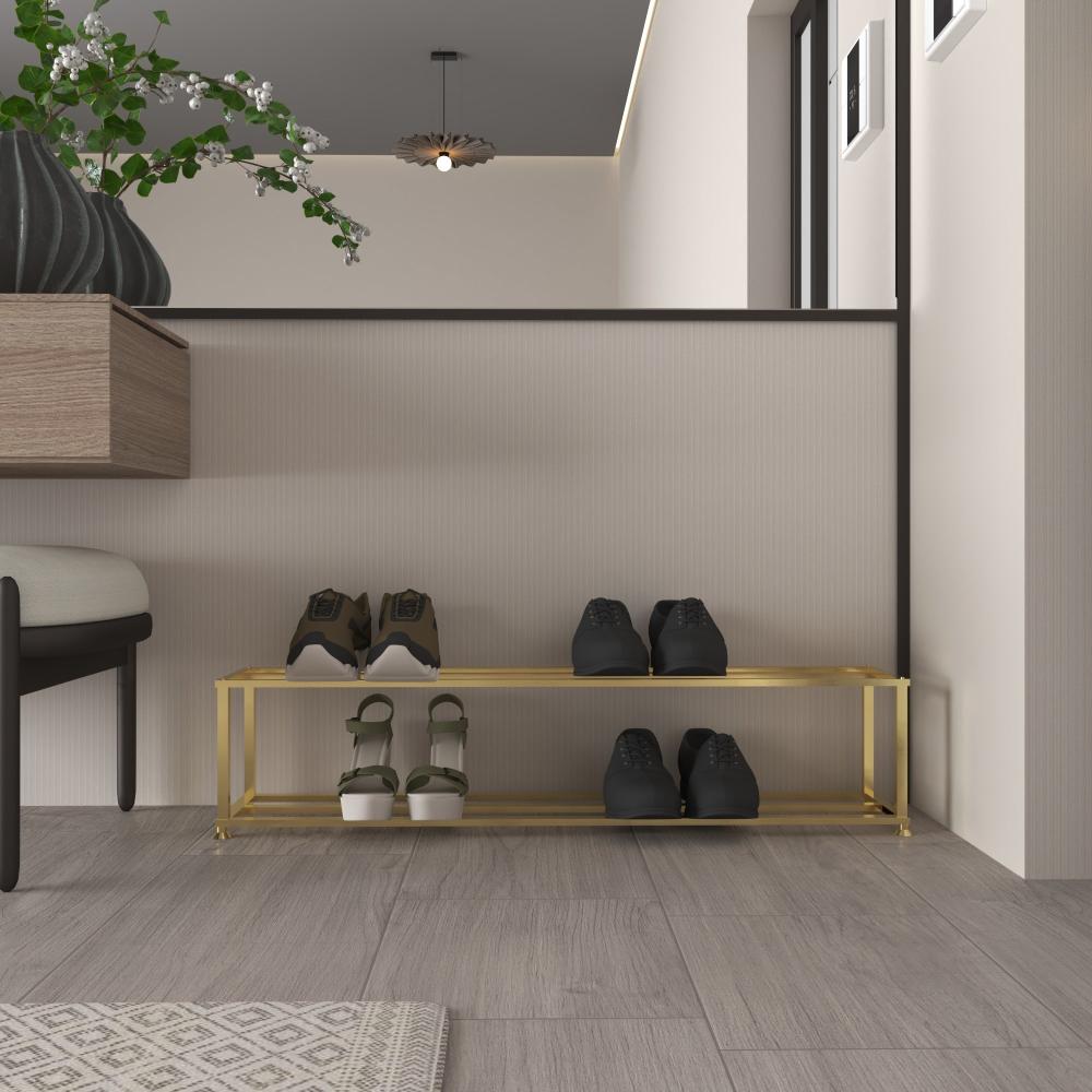 A modern, minimalist shoe rack in a luxurious gold finish, placed in a contemporary hallway. The rack holds two pairs of shoes on each of its two tiers, showcasing its functional and stylish design. The surrounding decor includes a wooden bench, a green plant in a dark vase, and a neutral-toned wall, enhancing the space's elegance and simplicity.