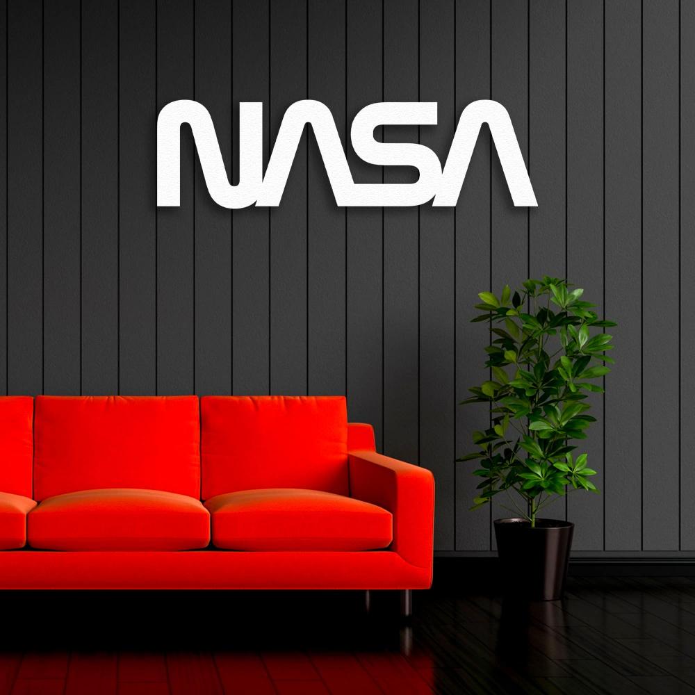 Modern living room featuring a bold red sofa against a black paneled wall. Above the sofa is a sleek white NASA metal sign wall art, complemented by a vibrant green potted plant on the right.