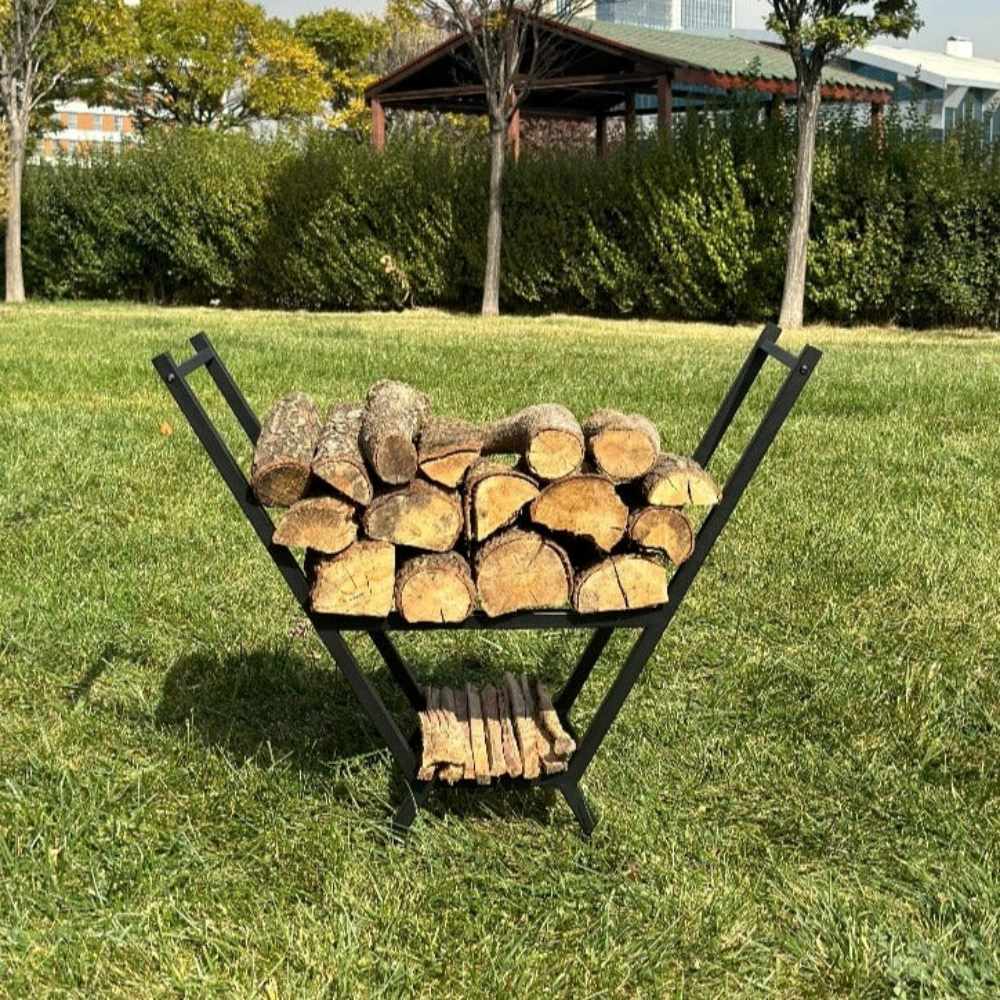 A black minimalist V-shaped metal wood holder displayed outdoors on green grass, holding stacked firewood with an additional compartment for kindling below.