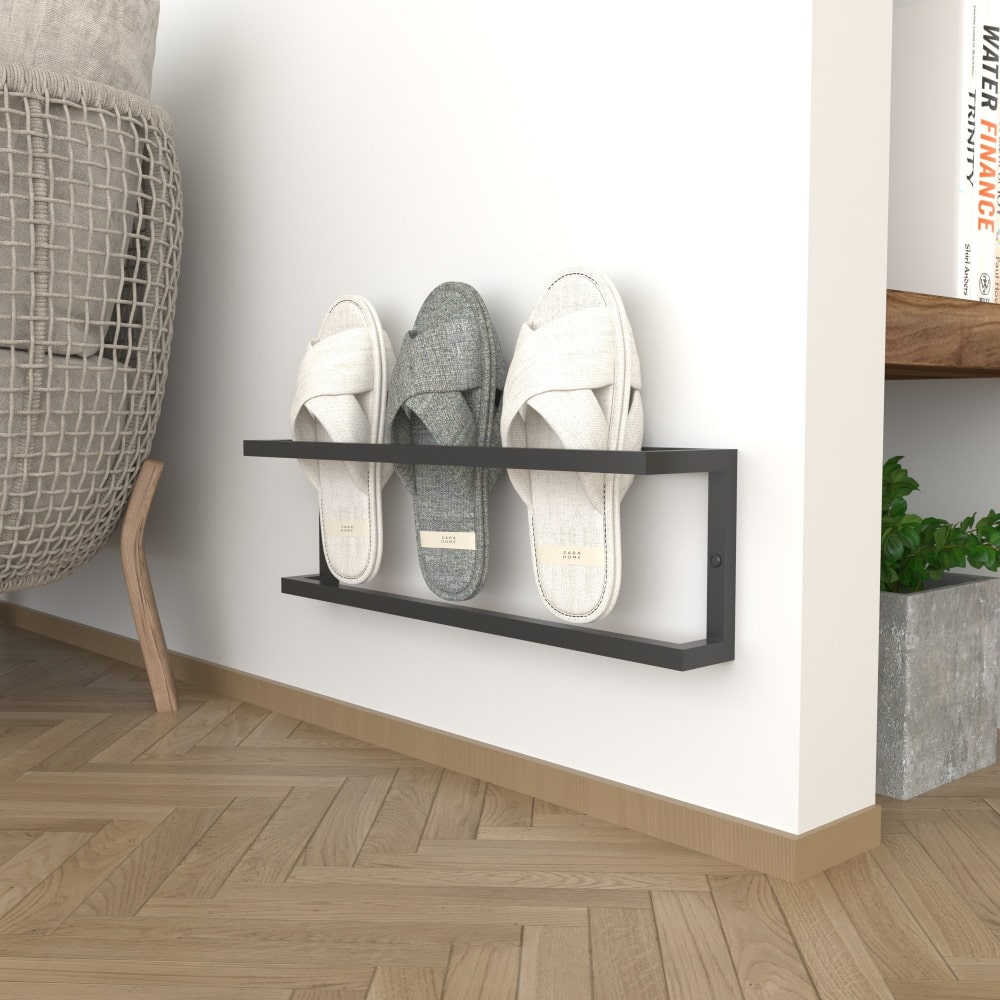 A minimalist black wall-mounted slipper rack on a plain background, holding three pairs of slippers, ideal for small spaces with a focus on functionality and style.