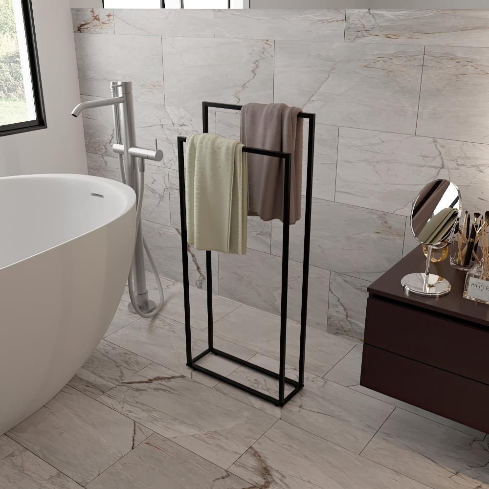 Modern black freestanding towel holder in a marble-tiled bathroom, holding two towels and placed next to a bathtub and vanity area