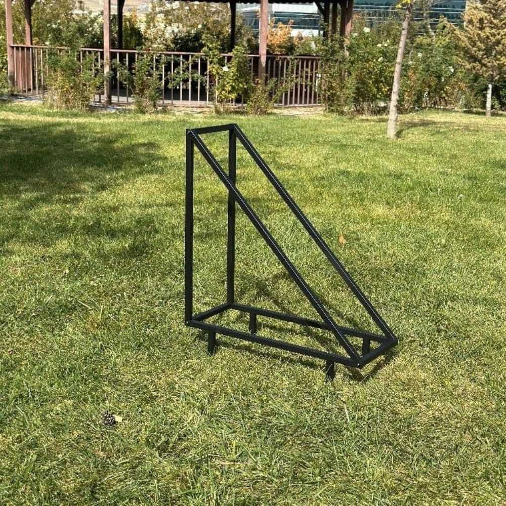 An empty black triangular metal wood rack, placed outdoors on a grassy field, showcasing its sturdy and minimalistic construction under natural light.