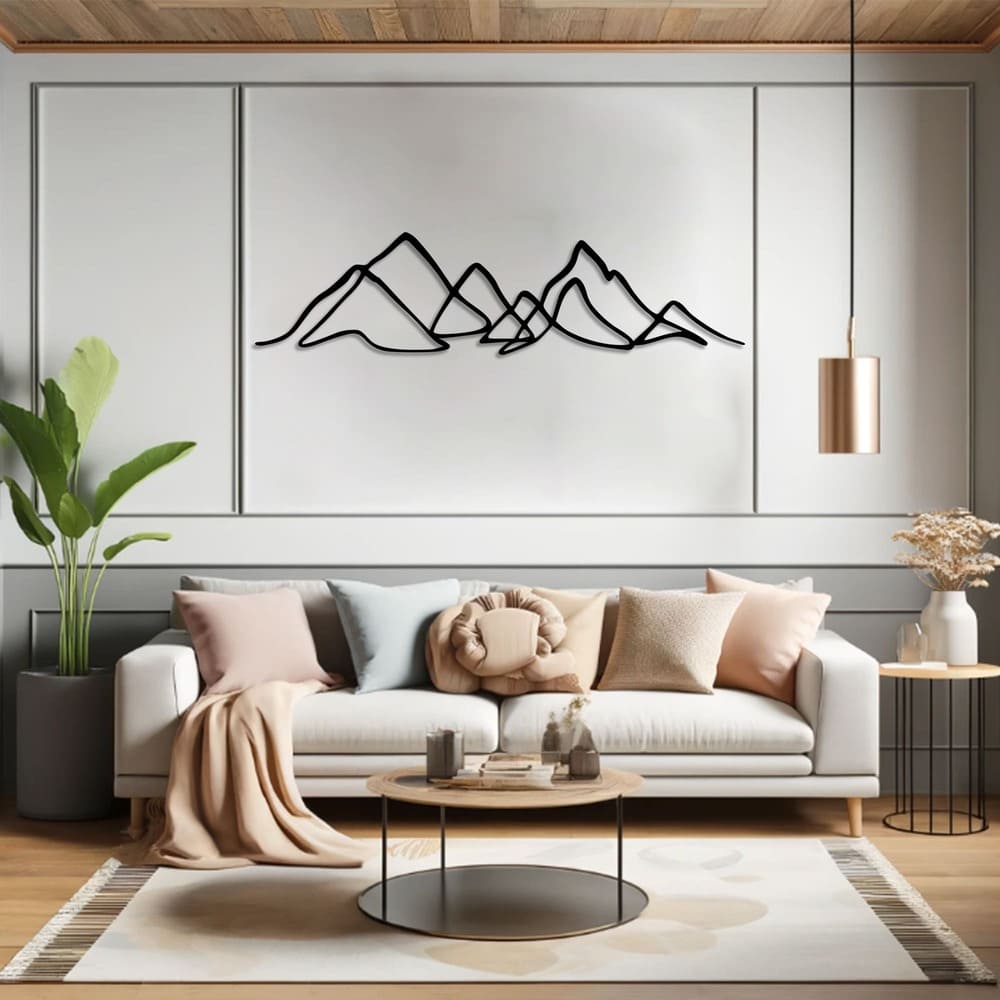 A modern metal wall art featuring a minimalist mountain range design, beautifully displayed above a cozy living room sofa with pastel-toned cushions and a warm, natural aesthetic.